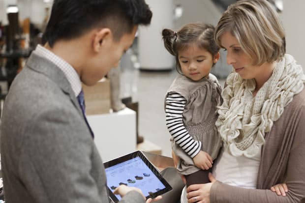 A Nordstrom salesperson shows a customer an online selection of shoes in-store