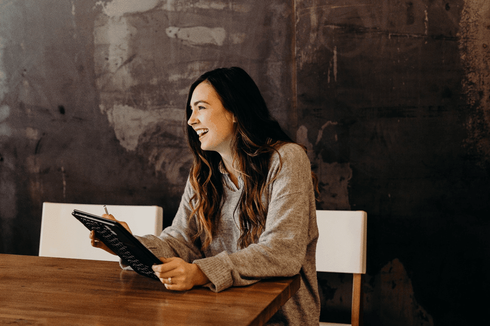 Woman smiling while holding a tablet.